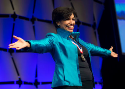 Paralympic ski champion, Rhodes Scholar, White House advisor and best-selling author Bonnie St. John smiling in a teal jacket and black shirt and wearing her Olympic medals at the 2014 Bridges Gala