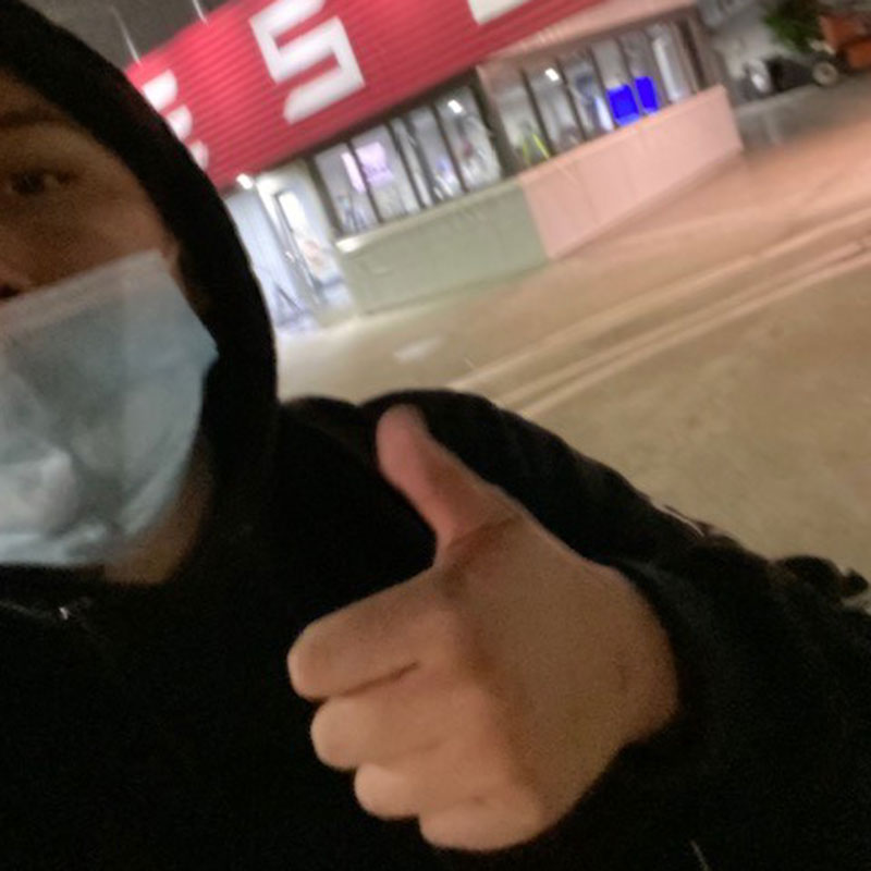 Ed P. of San Francisco giving the thumbs up sign outside of a Tesla dealership