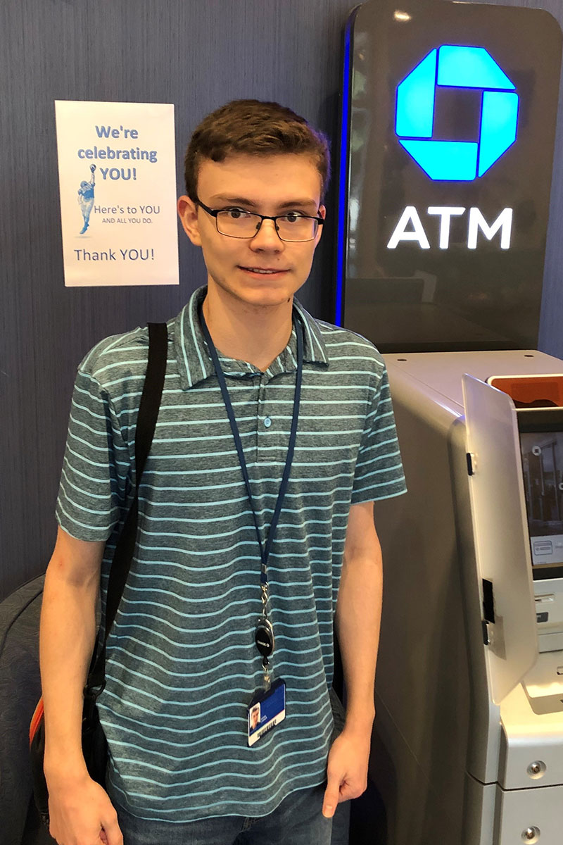 Daniel C., a Dallas - Ft. Worth participant, standing next to a ATM wearing his employee ID badge.